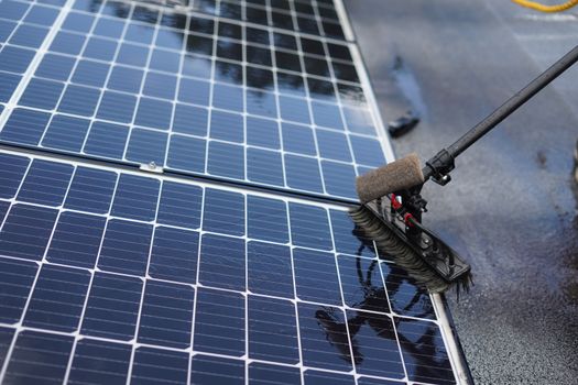 Zonnepanelen op een woning in Groningen die voorzichtig worden schoongemaakt met een zachte borstel op een bewolkte dag